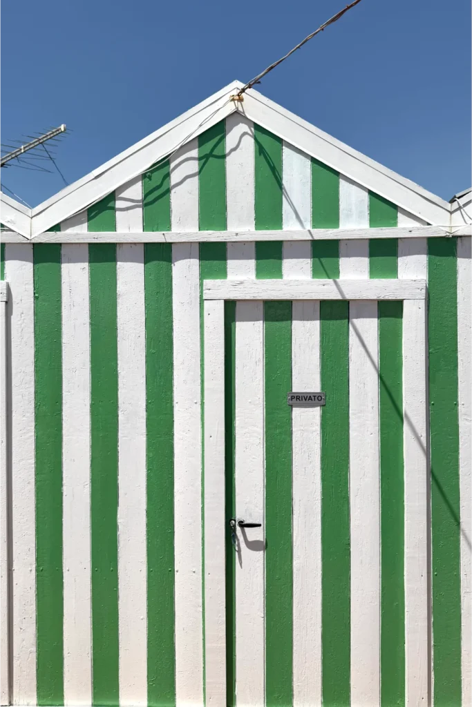 Casetta balneare Facciata di una capanna balneare in legno a strisce verticali verdi e bianche, con porta centrale e cartello "PRIVATO".