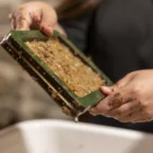 Mani che lavorano la pasta di carta su un setaccio